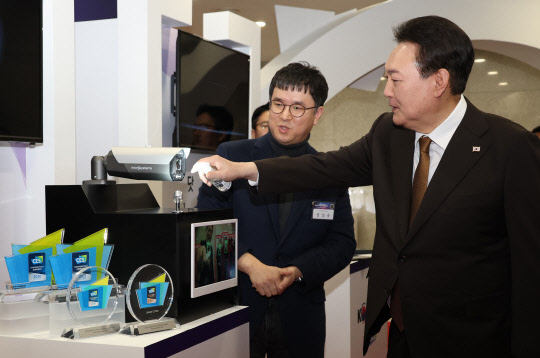 윤석열 대통령이 2일 서울 용산 대통령실 청사에서 열린 국제전자제품박람회(CES) 디지털 기술혁신 기업인과의 오찬 간담회에 앞서 2023 CES 최고 혁신상을 수상한 마이크로시스템의 인공지능(AI) CC(폐쇄회로)TV 카메라에 대해 설명을 듣고 분무기로 물을 분사하고 있다. 연합뉴스